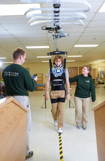 A patient aided by an exoskeleton during rehabilitation, guided by healthcare professionals.