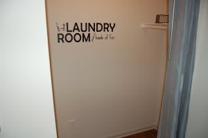 A simple laundry room with a decorative wall sign.
