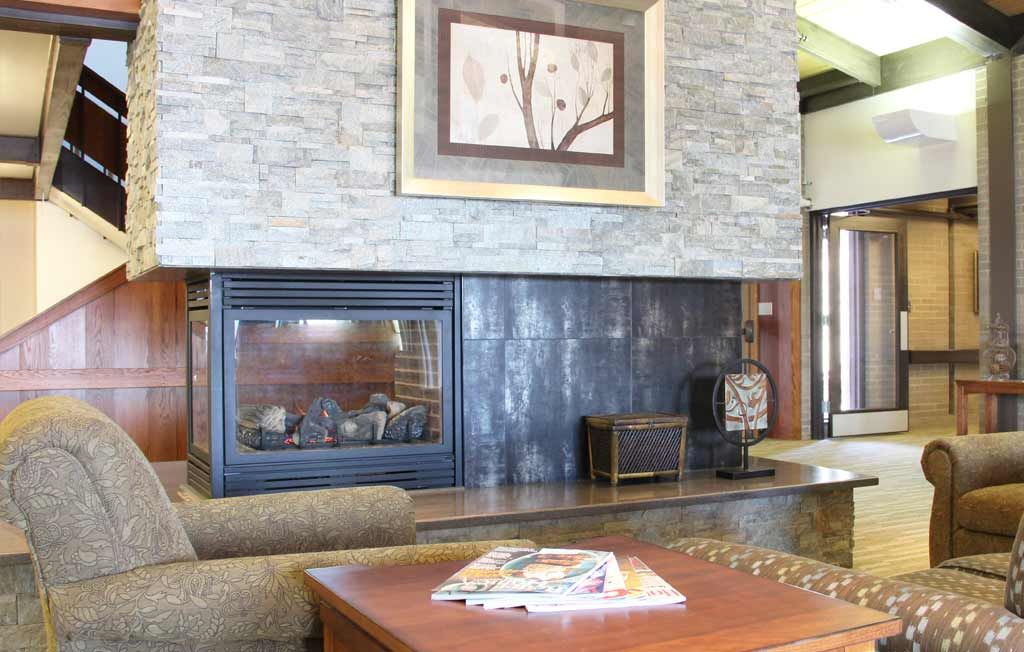 A cozy living room with a modern fireplace and artwork above.