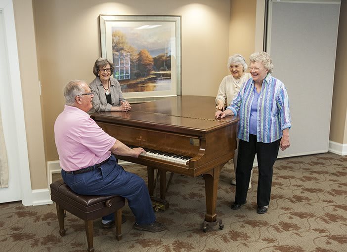 A group of elderly people gathered around a piano, enjoying music together.