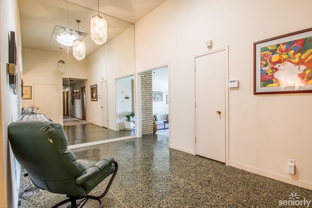 A modern hallway featuring a large mirror, stylish lighting fixtures, and a comfortable chair.