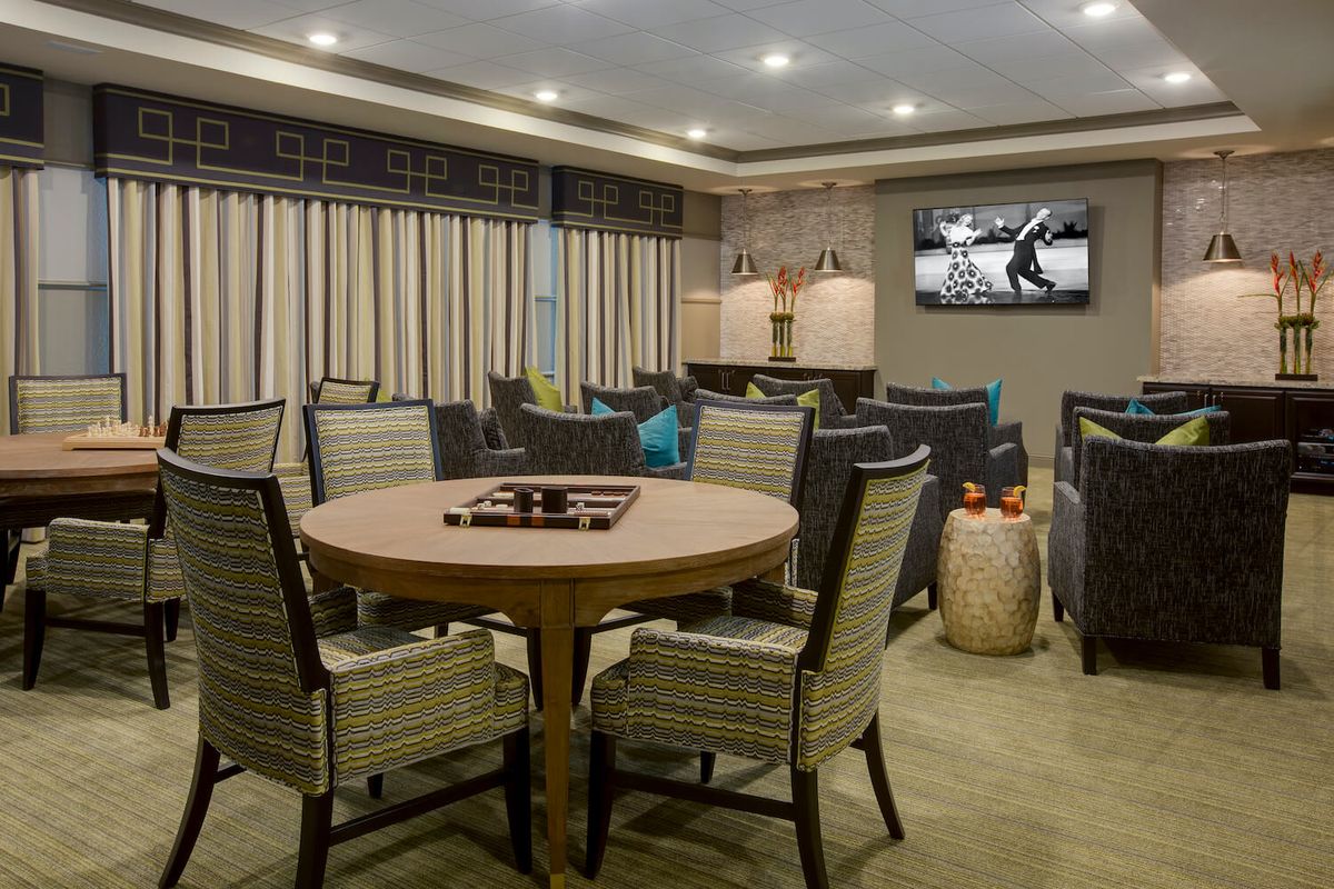 A modern lounge area featuring a round table with chairs, a wall-mounted television, and contemporary decor.