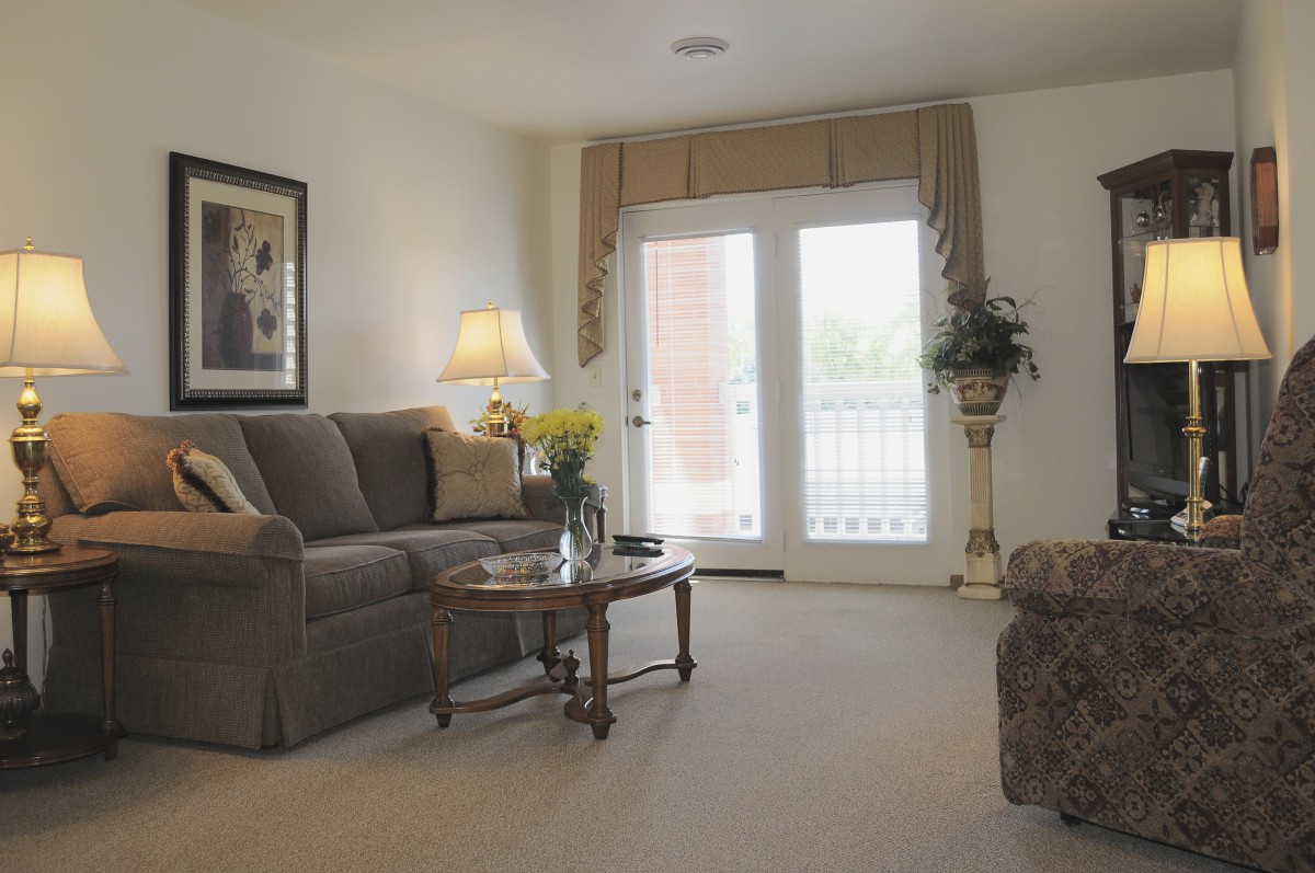 A cozy living room with a sofa, coffee table, and balcony doors.