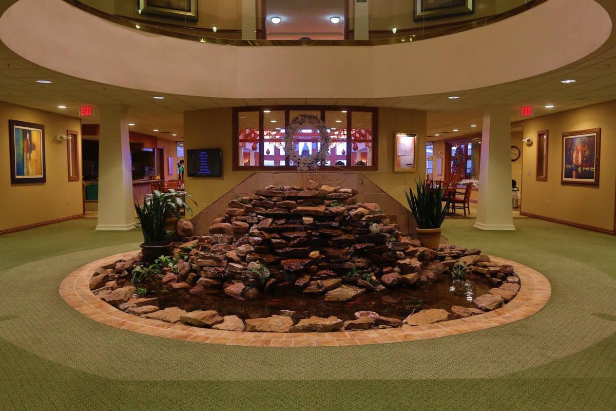An indoor atrium features a rock fountain surrounded by plants.