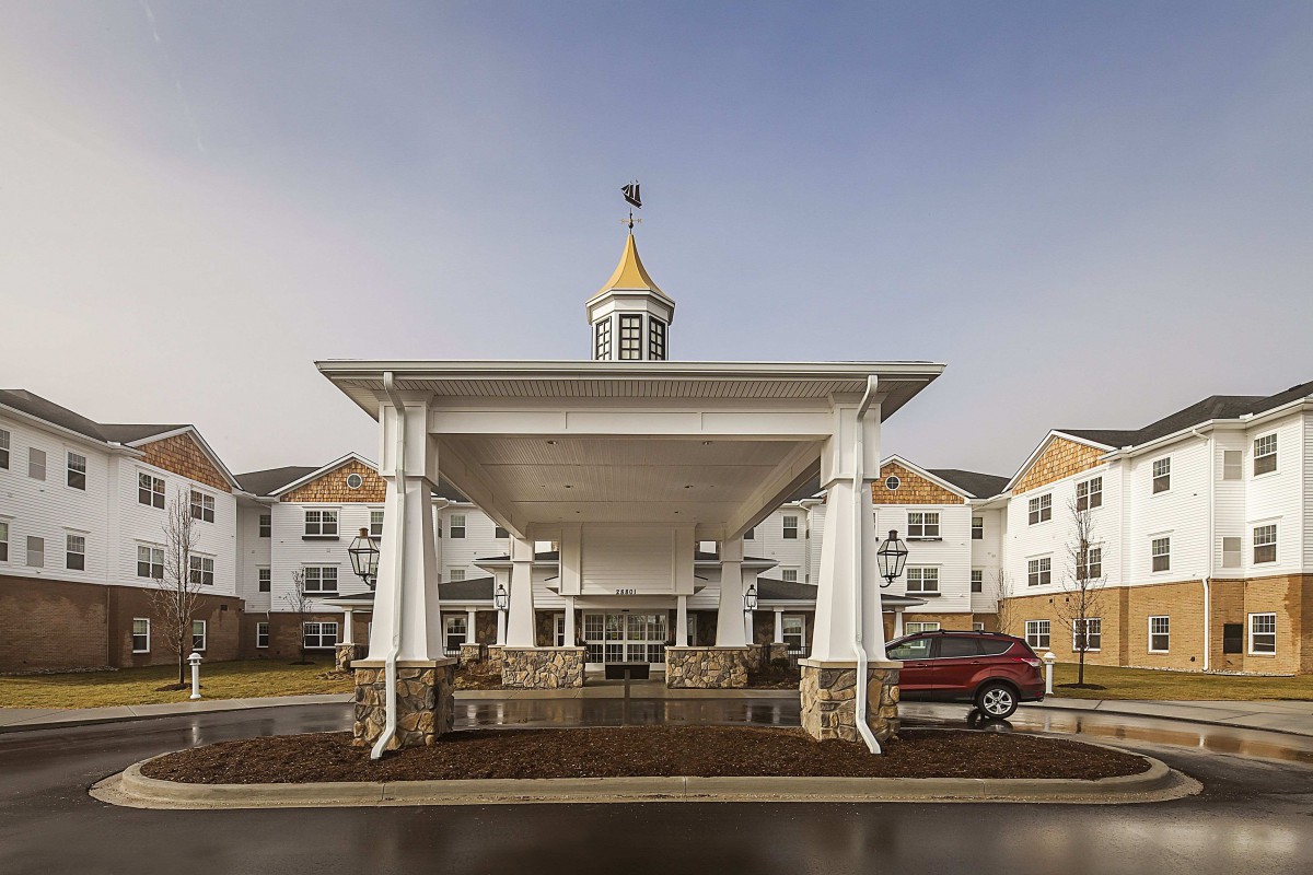 A building entrance with a large white canopy and a car parked nearby.