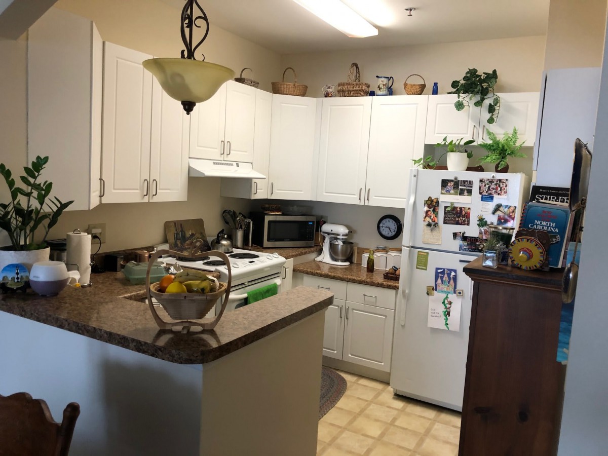 A cozy kitchen with white cabinets, a well-stocked countertop, and various appliances.