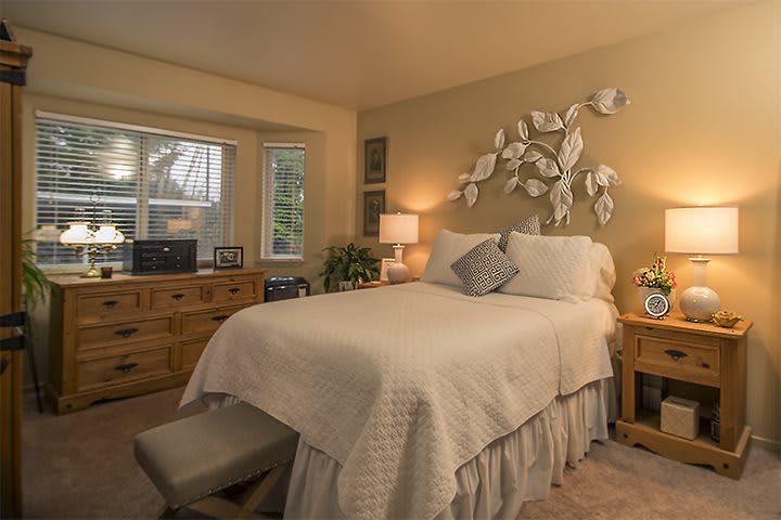 A cozy bedroom with elegant decor, featuring a comfortable bed, warm lighting, and decorative wall art.