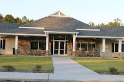 A small modern building with a stone facade and well-maintained lawn.