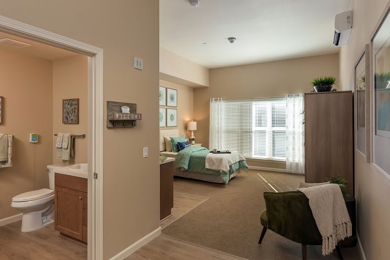 A cozy bedroom with a neatly made bed, large window, and modern furniture.