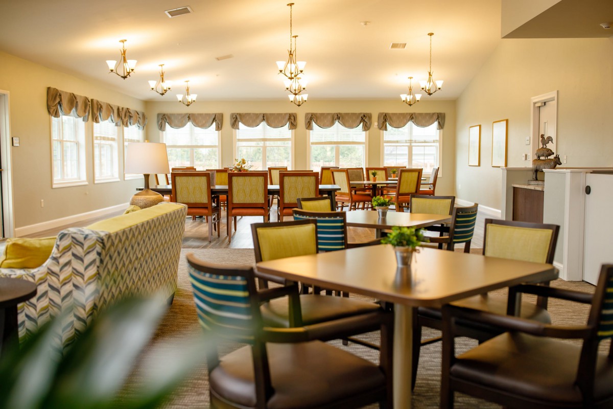 A well-lit dining area with tables, chairs, and large windows creating a cozy atmosphere.