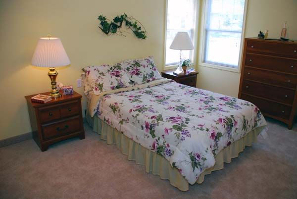 A cozy bedroom with floral bedding and two nightstands by the windows.