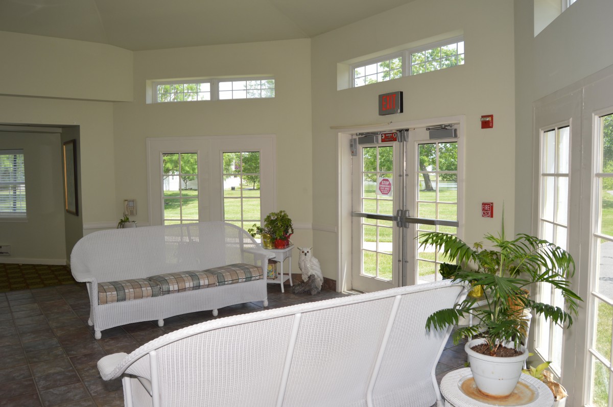A bright and airy lobby with white furniture, large windows, and indoor plants.