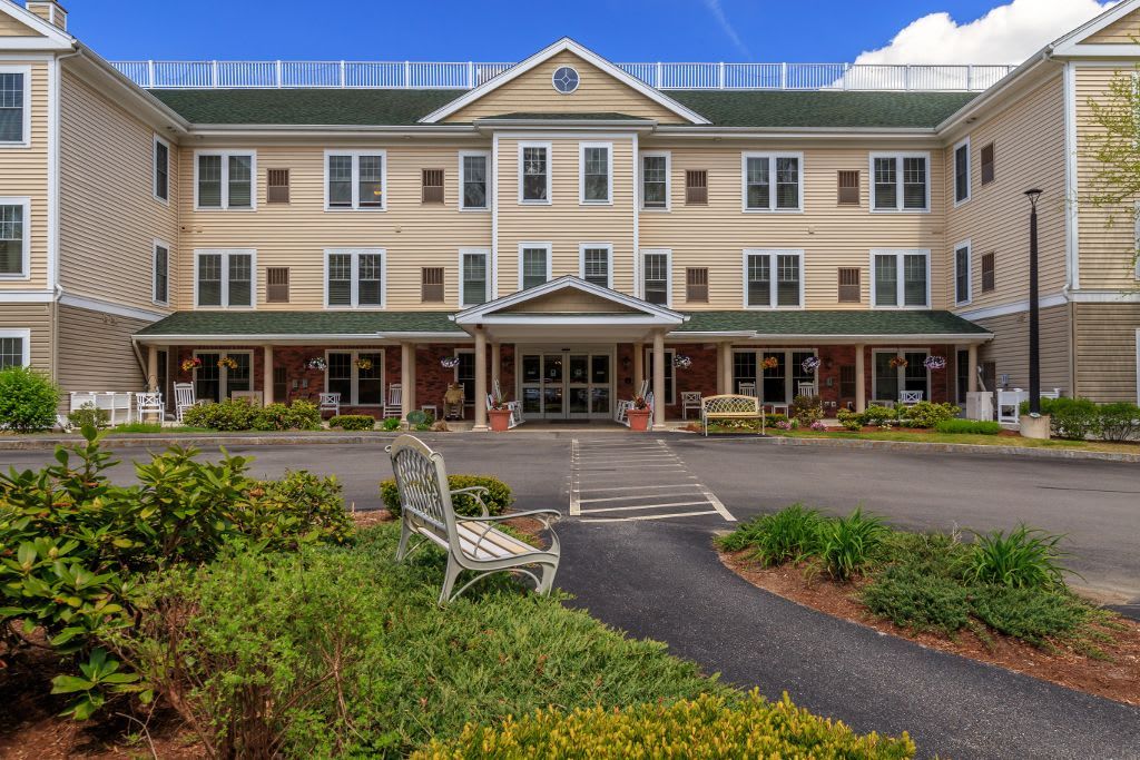 A three-story hotel or residential building with landscaped gardens and a welcoming entrance.