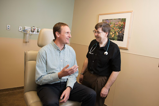A doctor and patient engage in a friendly conversation during a medical consultation.