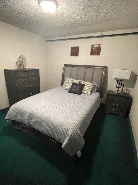 A neatly arranged bedroom featuring a bed, dresser, and nightstand with a lamp.