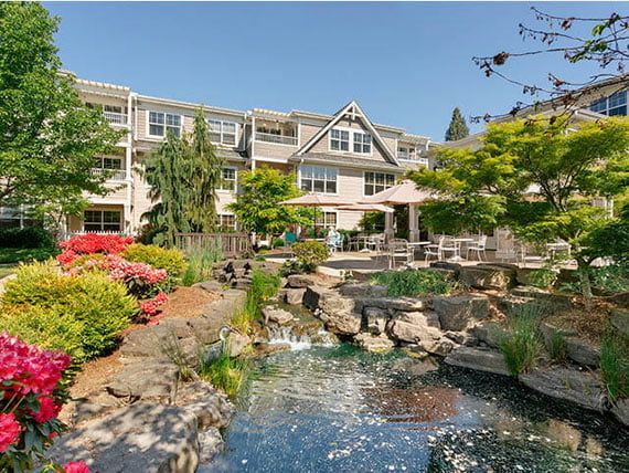 A serene view of a hotel surrounded by lush gardens and a tranquil pond.
