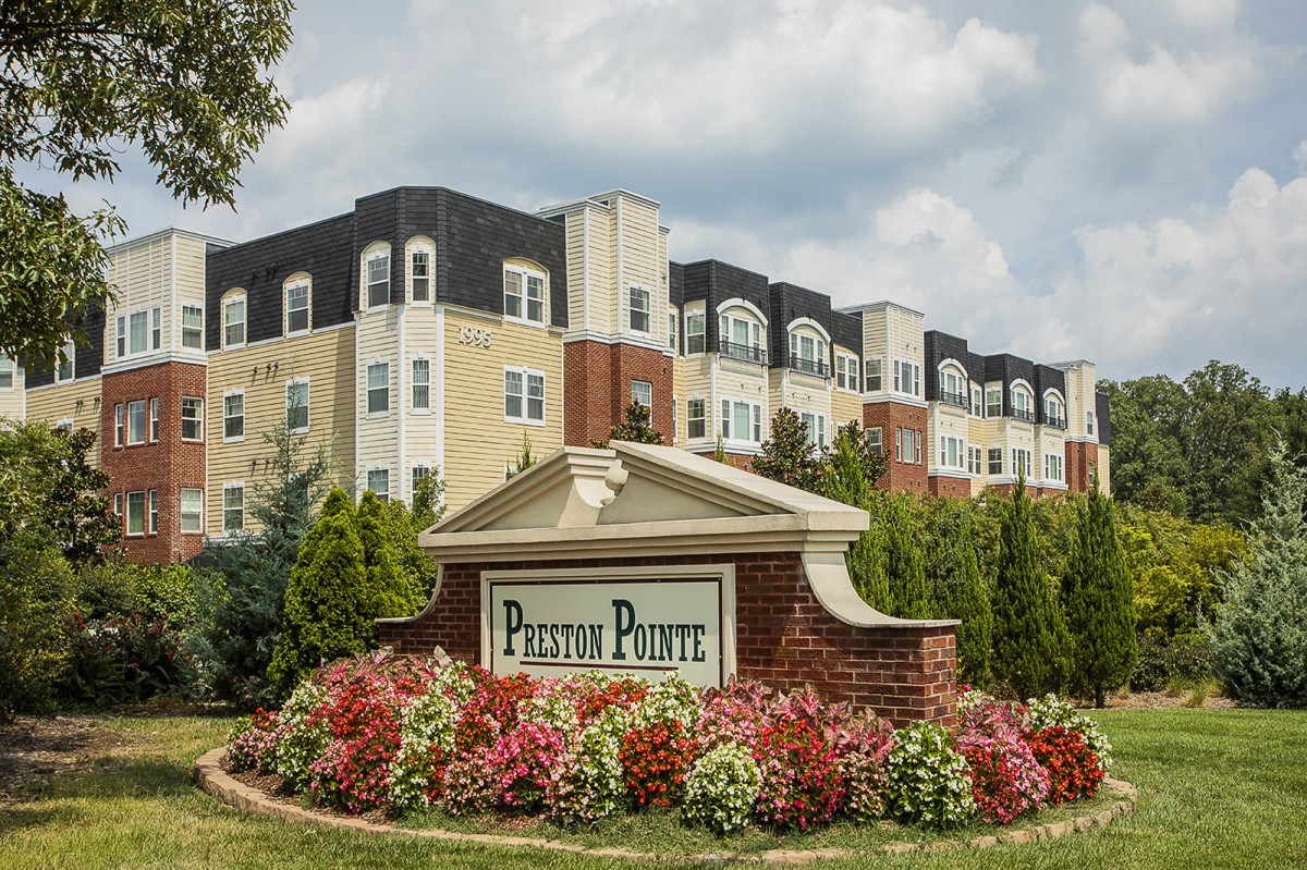 A well-maintained apartment complex with vibrant landscaping and prominent signage.