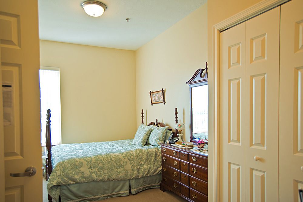 A cozy bedroom with a neatly made bed, dresser, and mirror.