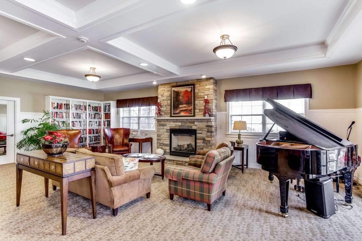 A cozy living room featuring a grand piano, fireplace, and bookshelves.