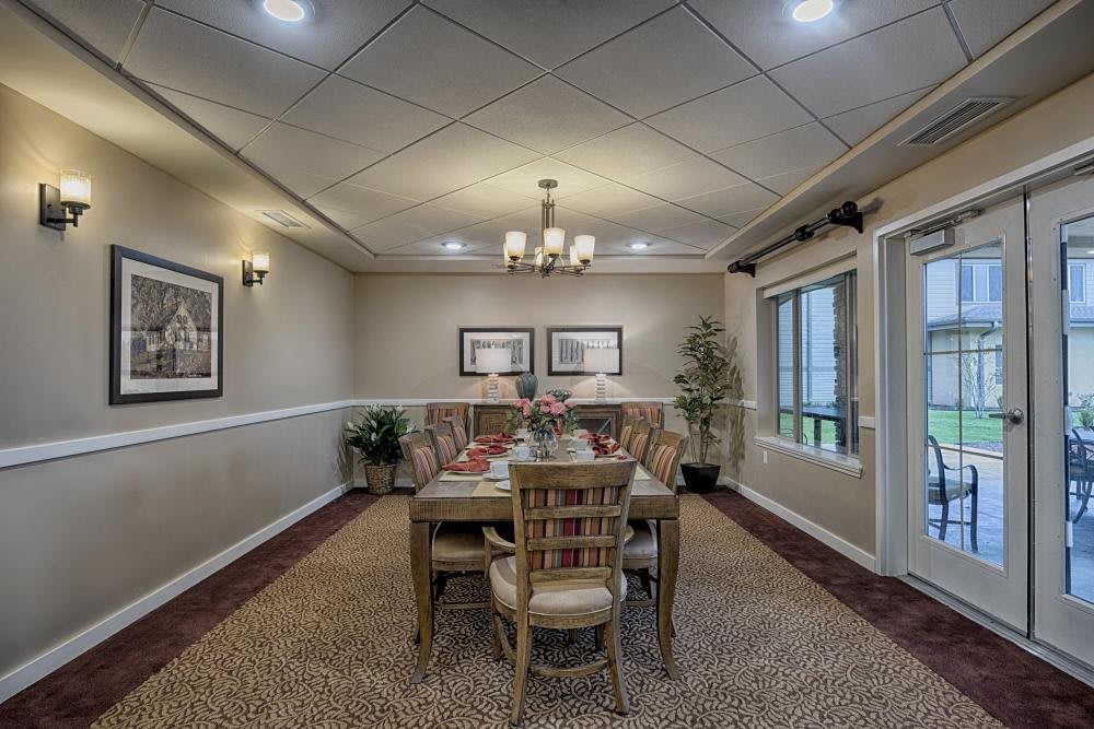 A well-decorated dining room with a central table and chairs, complete with artwork and a chandelier.