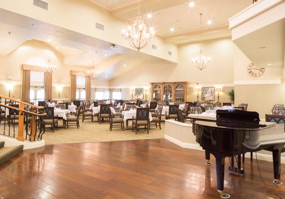 An elegant dining area with a grand piano and chandeliers.