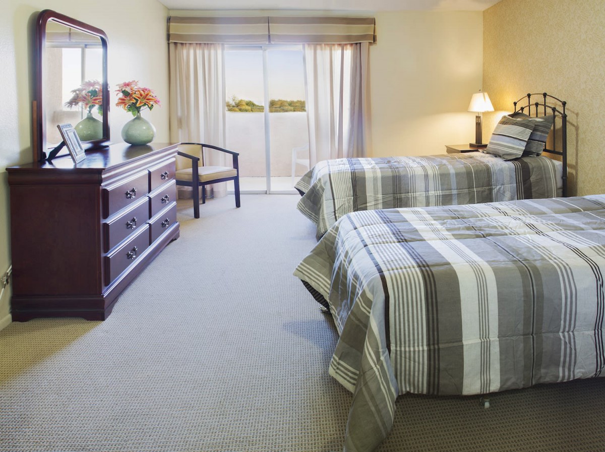 A cozy bedroom with twin beds, featuring striped bedspreads and elegant furniture.