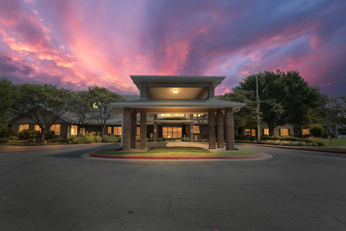 A building entrance illuminated during sunset with a dramatic sky overhead.
