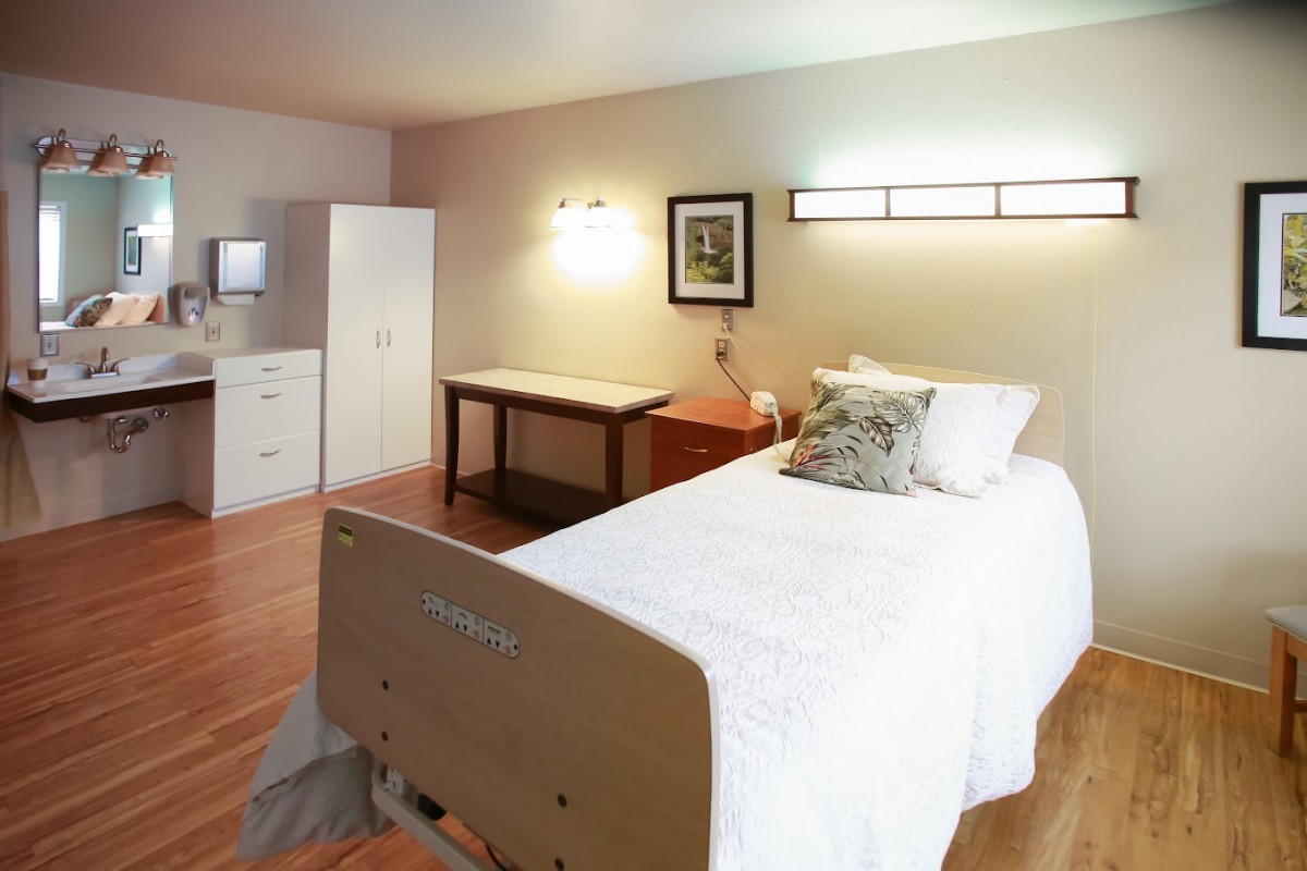 A well-organized hospital room with a single bed and simple furnishings.