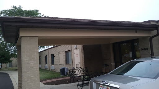 A view of a building with a carport and a parked car in front.