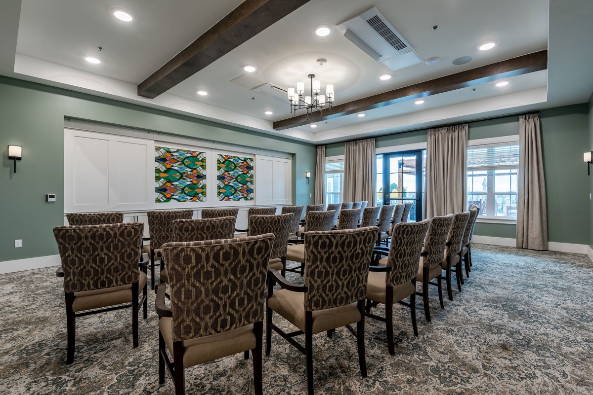 A well-lit conference room arranged with rows of patterned chairs facing a whiteboard.