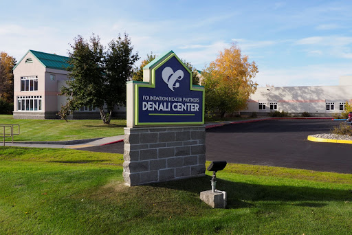 The sign for the Denali Center, a healthcare facility surrounded by greenery.