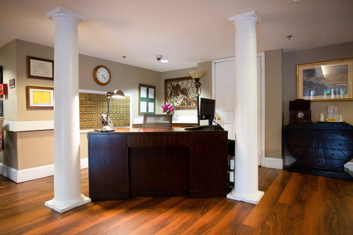 Reception desk area with wooden flooring and white columns.