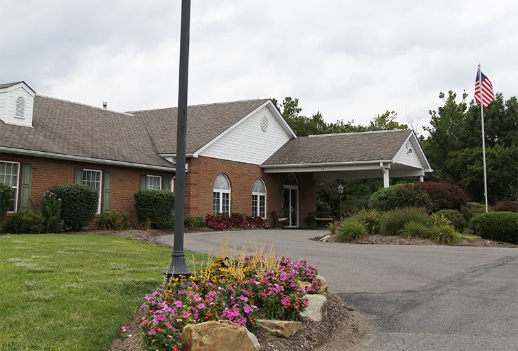 A brick building with a well-maintained garden and driveway.