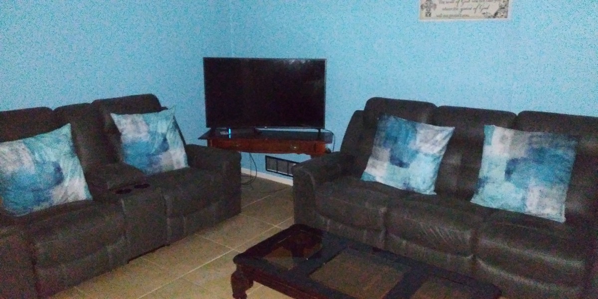 A cozy living room with blue walls, featuring a television, sofas, and a coffee table.