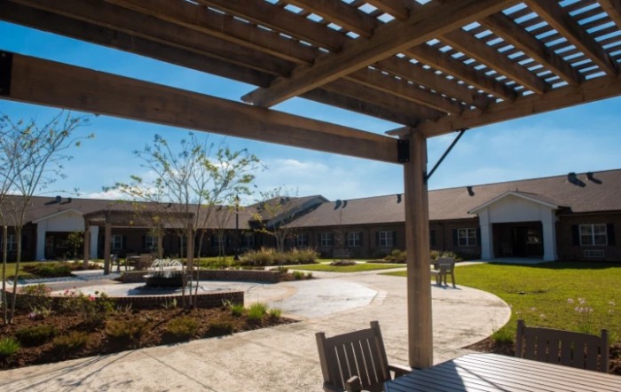 A sunny courtyard with a pergola, outdoor seating, and well-maintained landscaping.