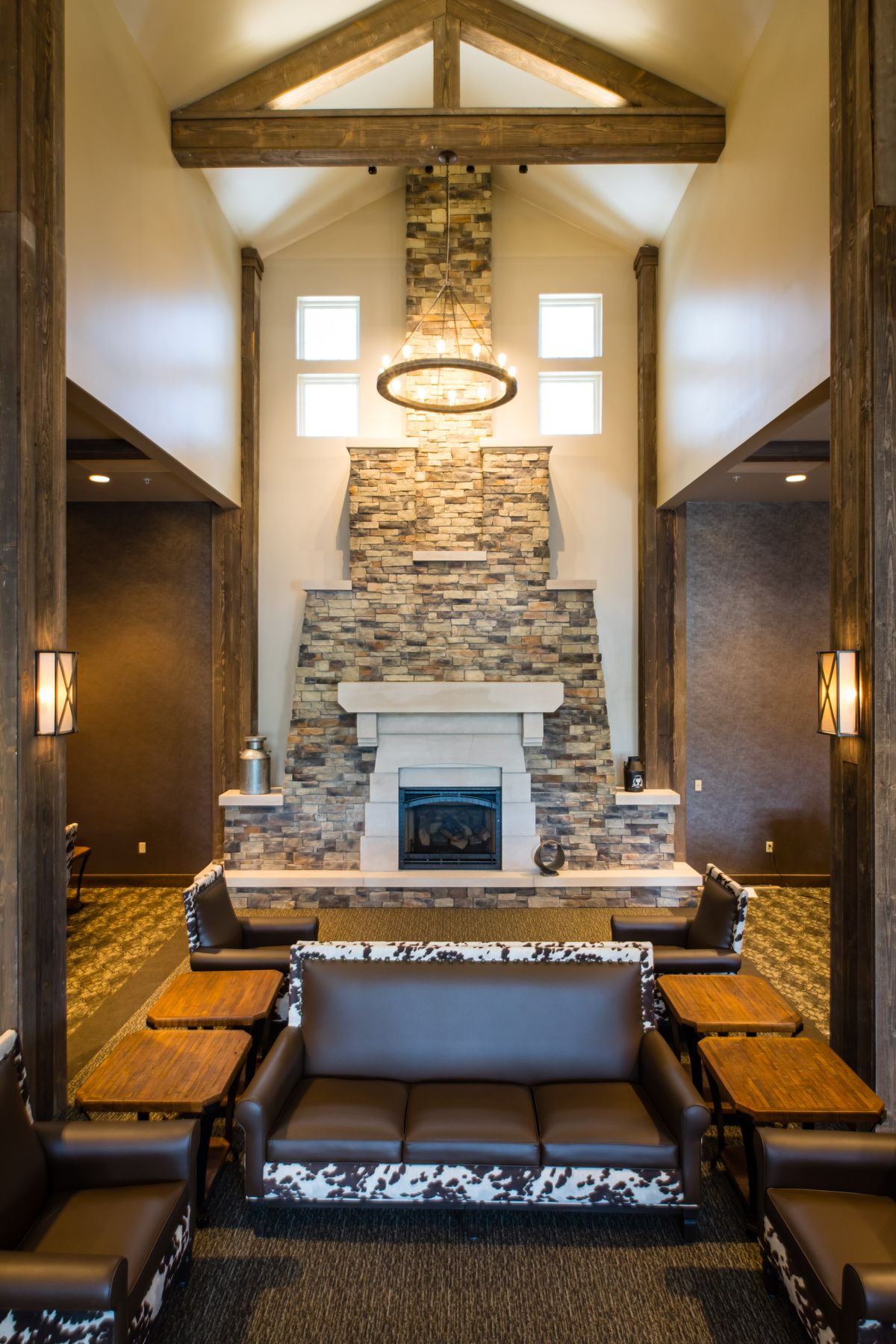 A modern living room with a stone fireplace and elegant chandelier.