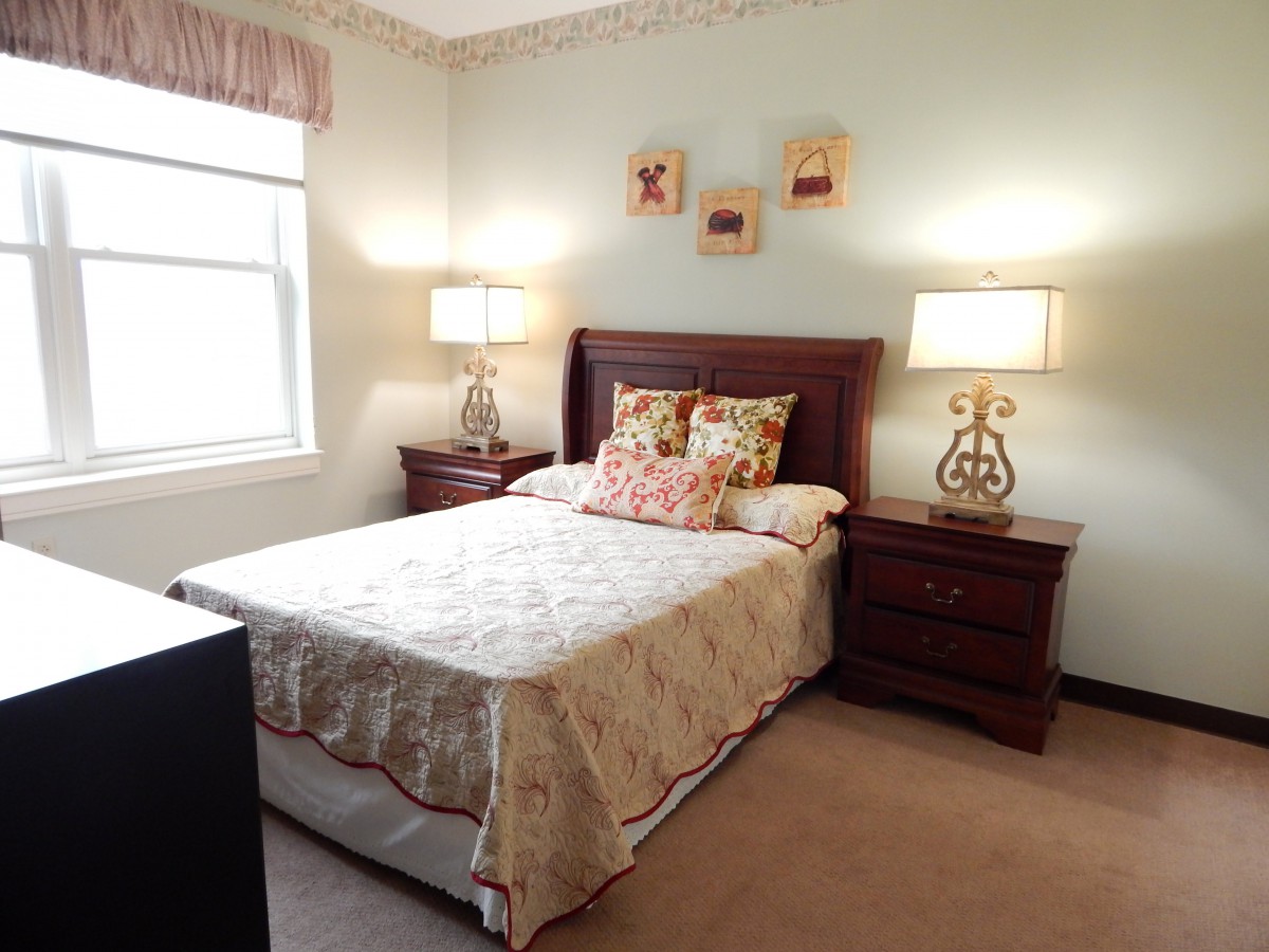 A cozy bedroom interior with a neatly made bed, two nightstands, and decorative lamps.
