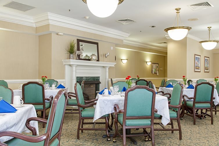 A well-decorated dining room with elegantly set tables and chairs, featuring a cozy fireplace.