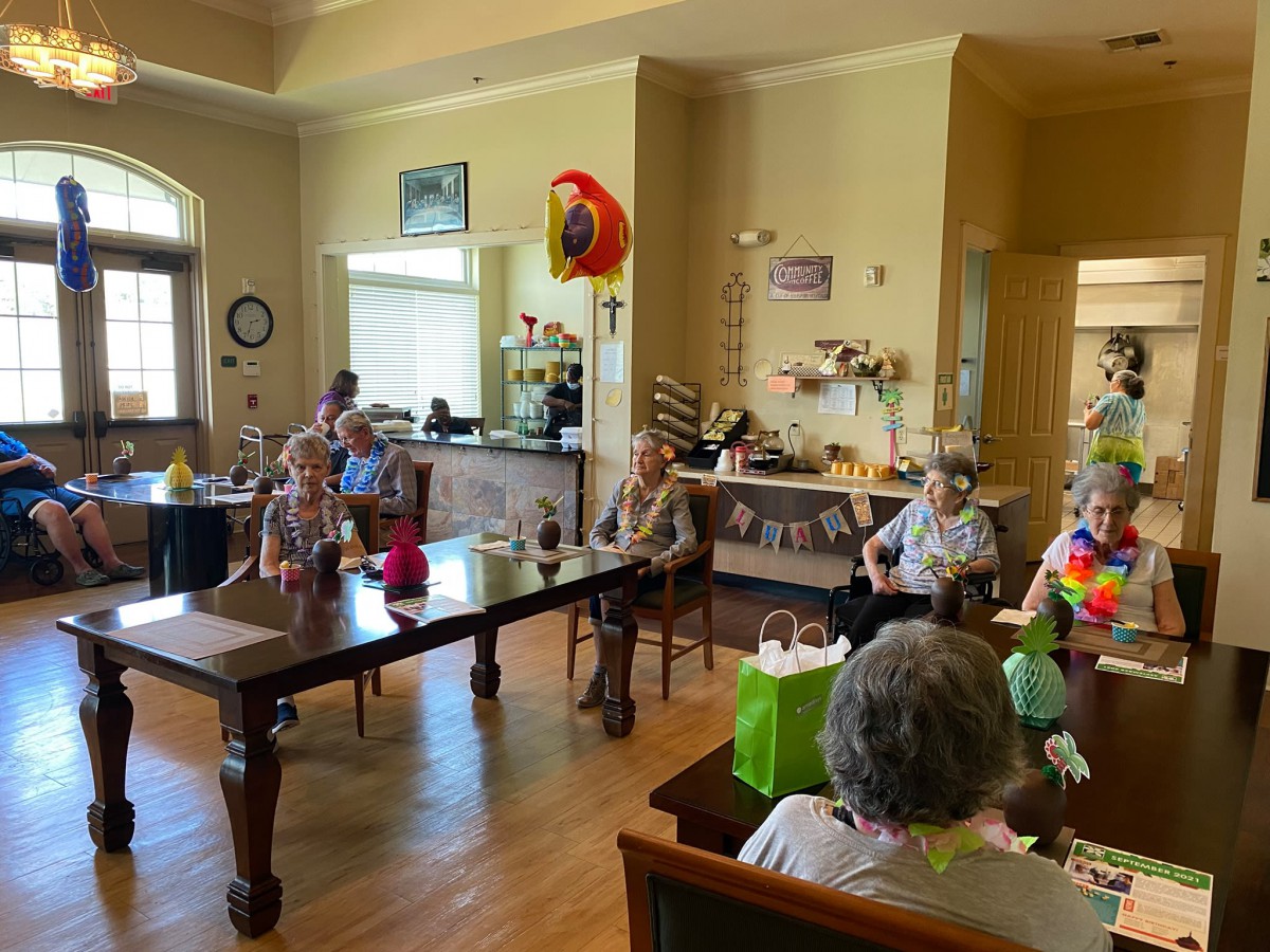 A group of seniors enjoying a celebration with balloons and decorations in a community room.