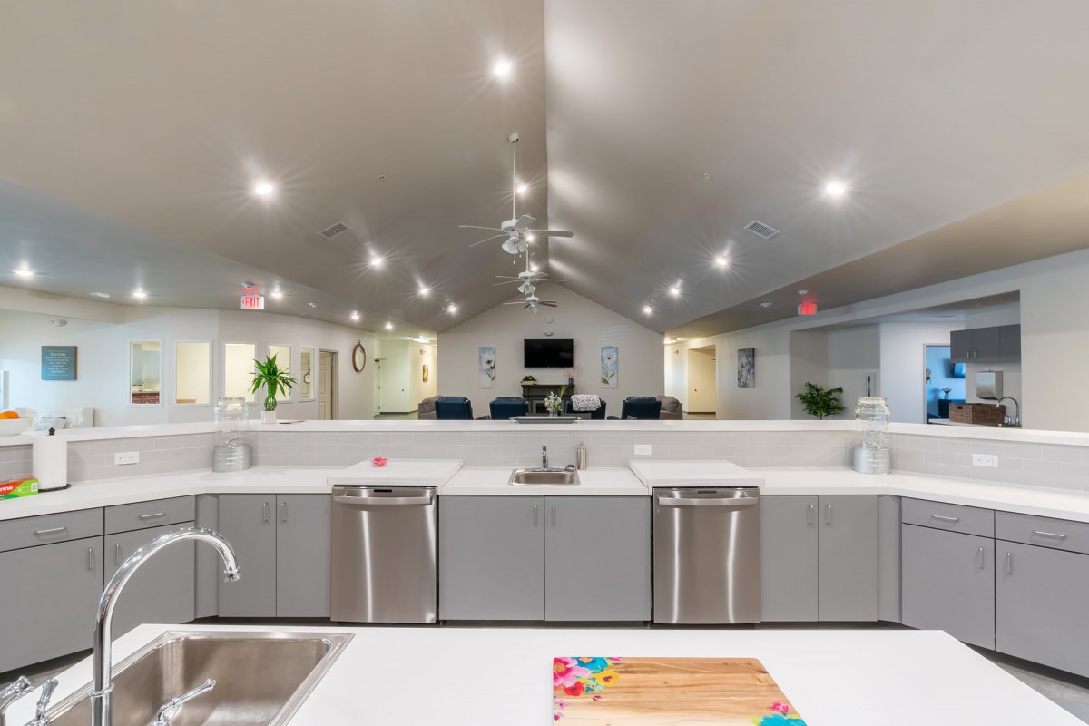 A modern kitchen with stainless steel appliances and bright overhead lighting.