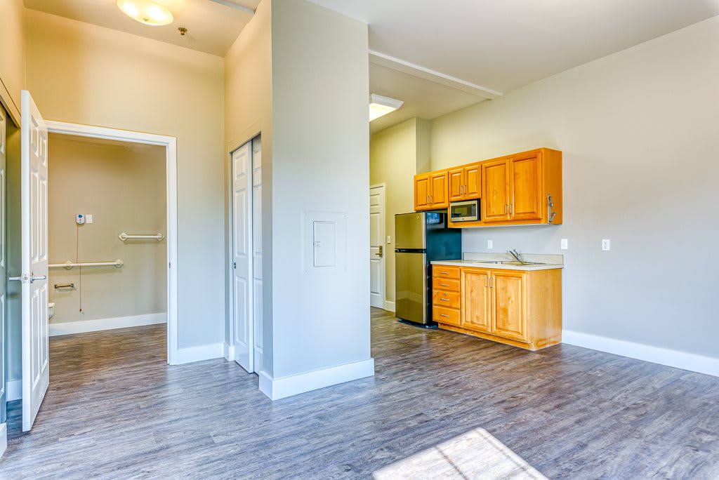 A bright apartment interior featuring a modern kitchen with wooden cabinets and hardwood flooring.