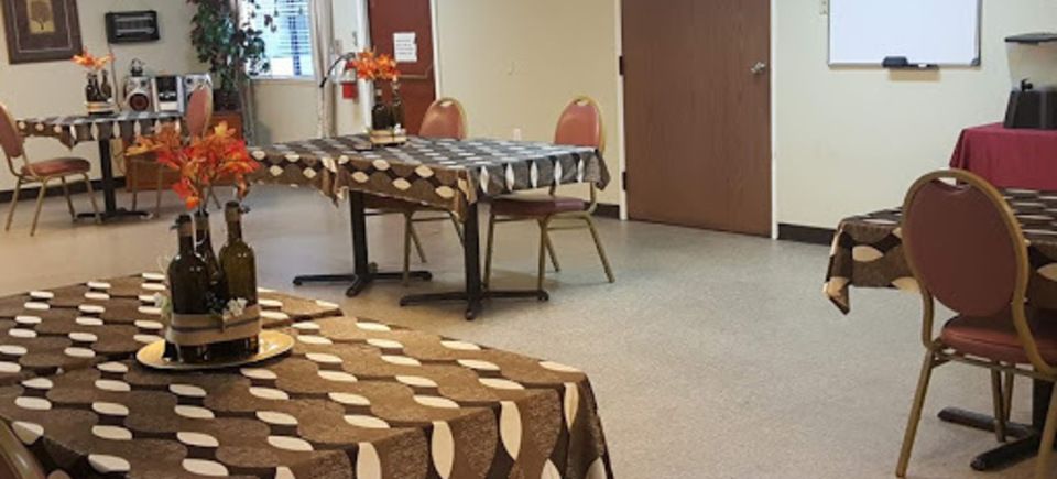 A room with tables covered in patterned tablecloths, chairs arranged around them.