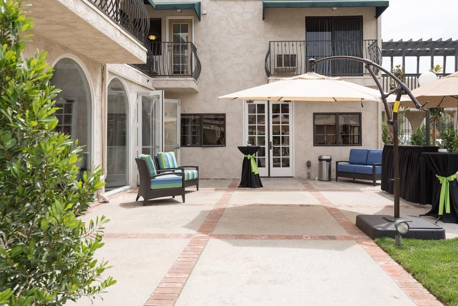 A spacious courtyard with seating area and an umbrella, surrounded by a building with balconies.