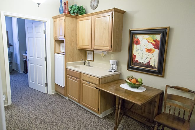 A compact kitchenette with wooden cabinets, a sink, and decorative artwork on the wall.