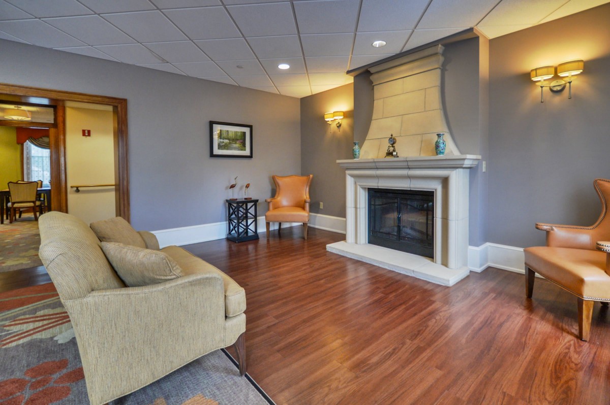 A cozy living room featuring a fireplace, sofa, and wooden flooring.