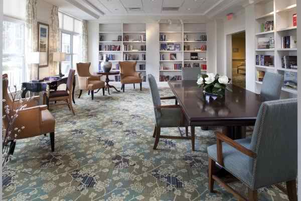 A cozy library space with bookshelves, chairs, and a large table.