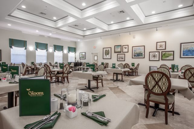 An elegant restaurant dining room with neatly arranged tables and chairs, featuring tasteful decor on the walls.