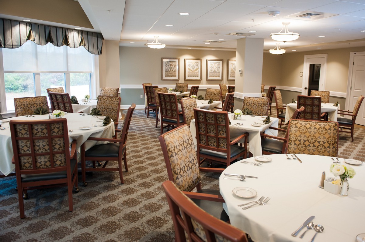 A neatly arranged dining area with round tables and cushioned chairs, ready for guests.