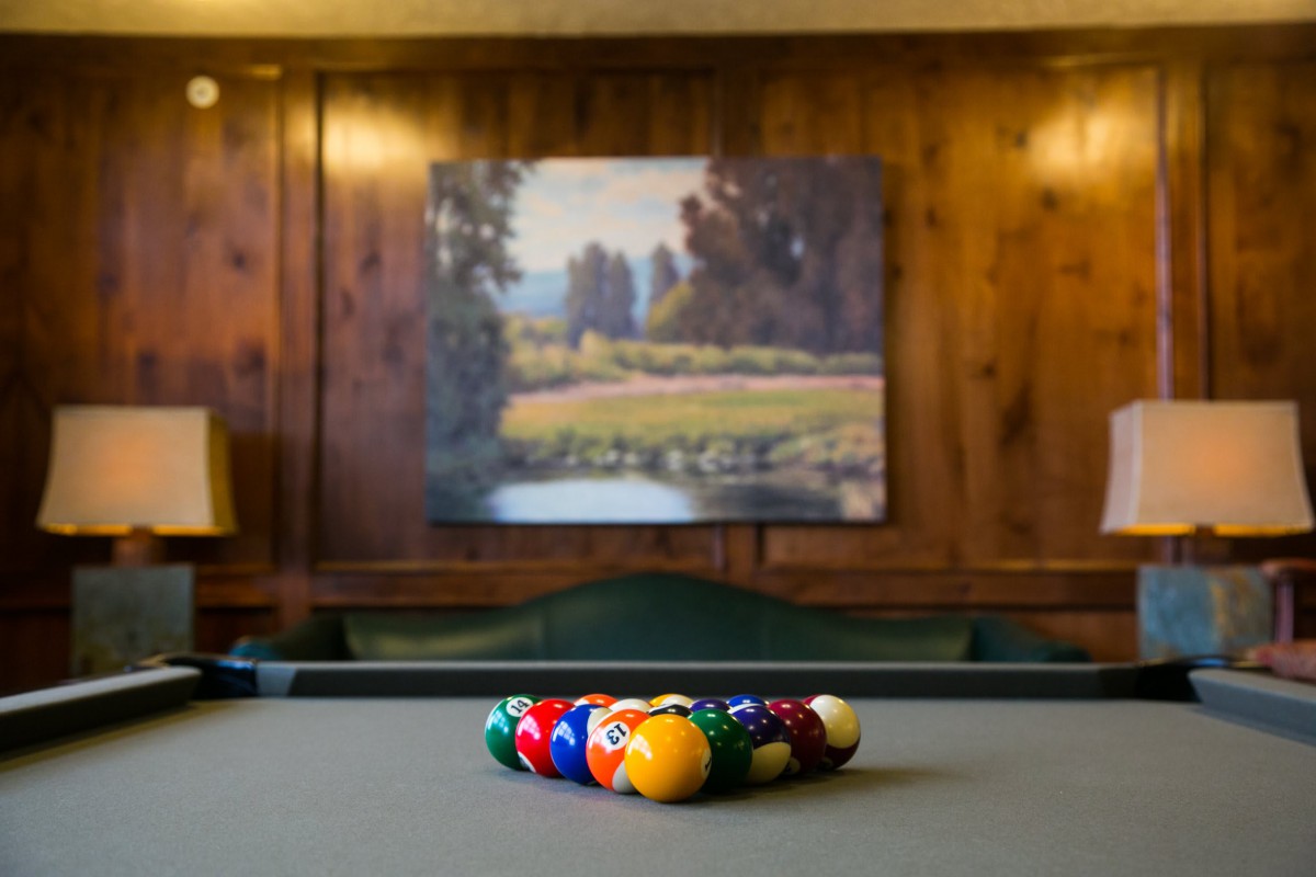 A neatly arranged set of pool balls on a billiards table in a cozy game room.