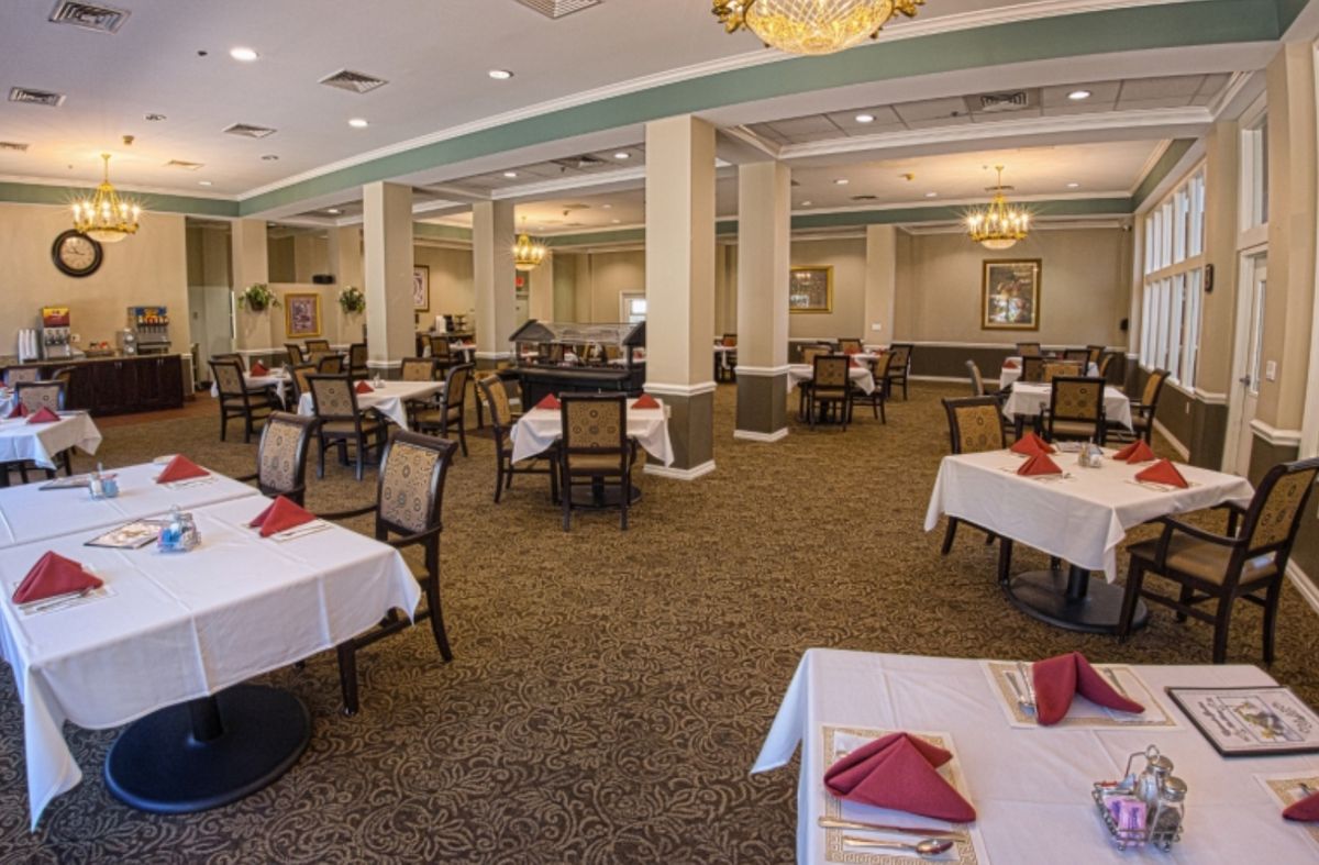 An elegant dining area with neatly arranged tables and chandeliers.